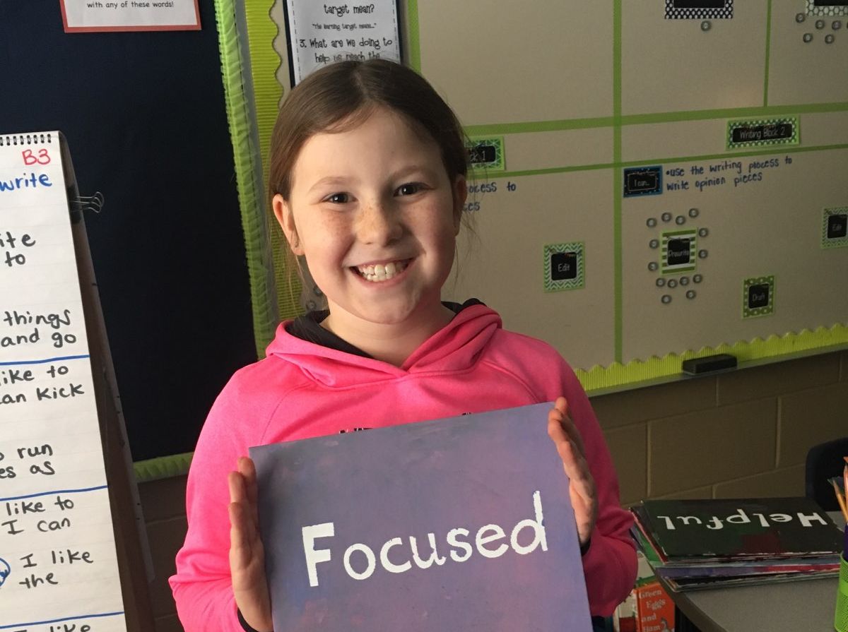 Girl at Jaguar Academy holding a sign that reads "Focused!"